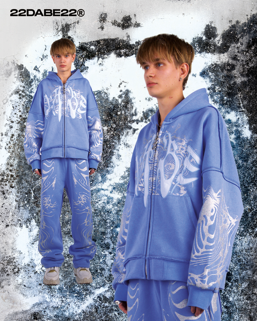 A light blue hooded jacket with a split zipper at the back. The jacket features a glitter screen print and embroidery appliqué on the front, with additional glitter screen print detailing on the sleeves. The jacket has an oversized fit and a peached interior lining for a cozy feel. The custom 22 puller adds a unique touch to the zipper.