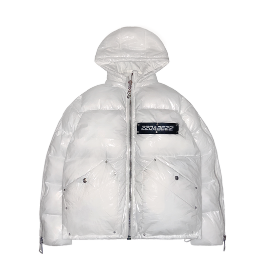 A white puffer jacket from 22DABE22, made of high-quality nylon fabric and cotton down filling, featuring custom logo rivets and buttons, detachable hood, and adjustable drawcords on the bottom hem. The jacket has an oversized fit, with sleeves that can be unzipped for unrestricted movement and ample storage space with one inside pocket and two side pockets. The logo tape at the chest adds a touch of branding.